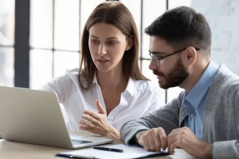 Dizüstü bilgisayar başında birlikte çalışan mentor ve danışan